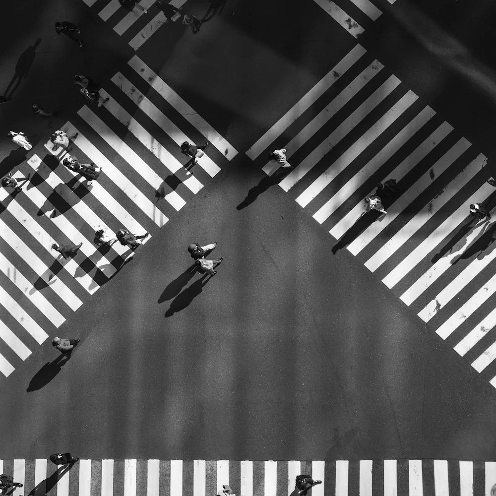 Pessoas atravessando faixas de pedestres em diagonal, vistas de cima