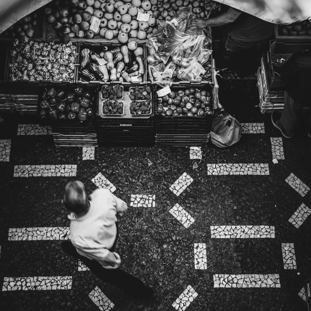 Pessoa caminhando até uma banca de frutas, vista de cima